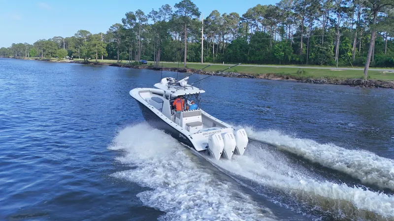 Slide: The Image of 2022 Yellowfin 34 boat cruising on a scenic river with lush green trees. - 13