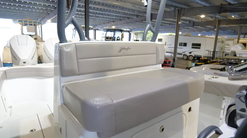 Slide: The Image of 2022 Yellowfin 34 boat interior with cushioned seating in a covered marina. - 18