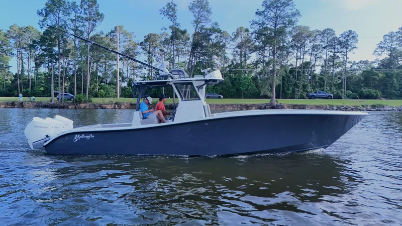 Slide: The Image of 2022 Yellowfin 34 boat cruising on a calm lake with trees in the background. - 4