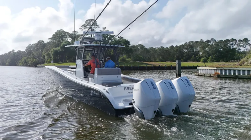Slide: The Image of 2022 Yellowfin 34 boat cruising on a river with triple outboard engines. - 9