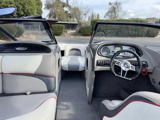 Slide: The Image of 2006 Malibu 247 LSV boat interior with gray and white seating, steering wheel, and dashboard. - 13