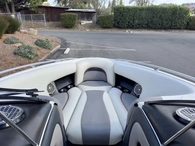 Slide: The Image of 2006 Malibu 247 LSV boat interior with gray and white seating in a parking area. - 14