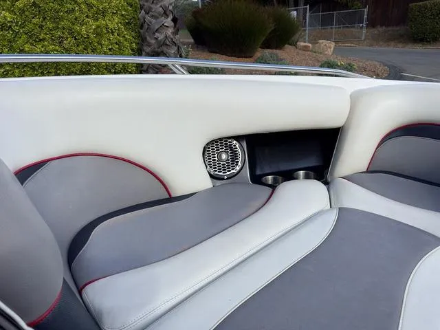 Slide: The Image of 2006 Malibu 247 LSV boat interior with white and gray seating, speaker, and cup holders. - 15