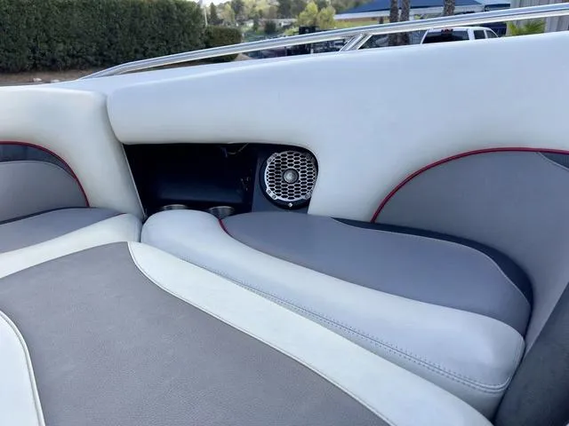 Slide: The Image of 2006 Malibu 247 LSV boat interior with gray and white seating, featuring a speaker. - 16