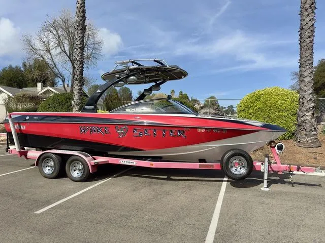 Slide: The Image of Red 2006 Malibu 247 LSV Wake Setter boat on trailer in parking lot. - 3