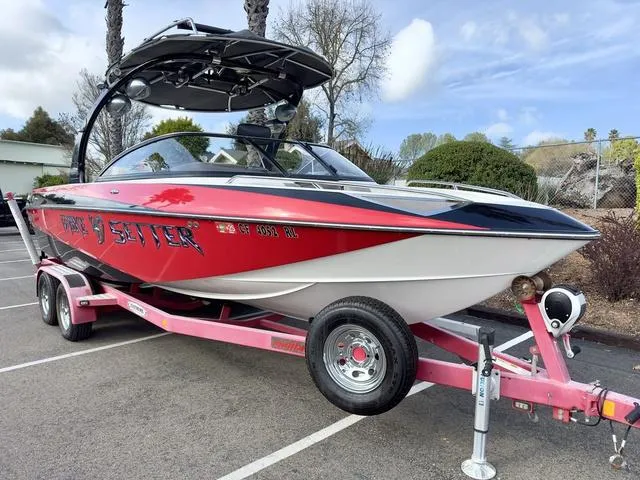 Slide: The Image of 2006 Malibu 247 LSV boat on pink trailer, parked outdoors, featuring sleek red and white design. - 4