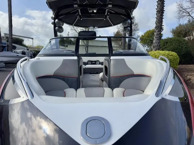 Slide: The Image of 2006 Malibu 247 LSV boat interior with gray and white seating, open cockpit, and clear windshield. - 5