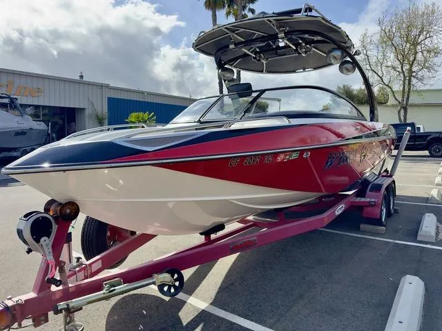 Slide: The Image of 2006 Malibu 247 LSV boat on trailer, red and white design, parked outdoors. - 7