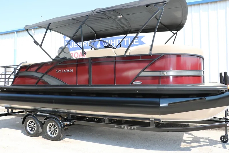 Slide: The Image of 2025 Sylvan L3 CLZ DH pontoon boat with red and black design on a trailer. - 14
