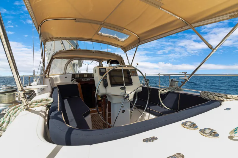 Slide: The Image of 2009 Hylas 54 yacht cockpit with steering wheel, under a tan canopy, sailing on open sea. - 26