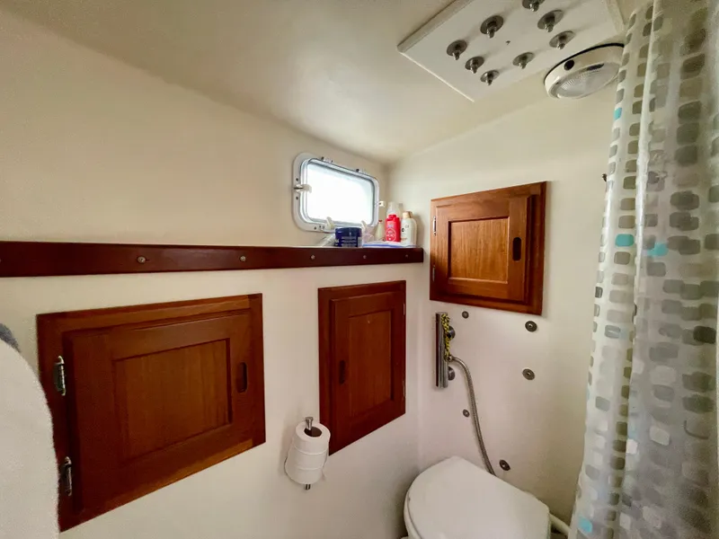 Slide: The Image of Small boat bathroom with wooden cabinets, shower, and porthole window. Beal 34, 2004 model. - 40