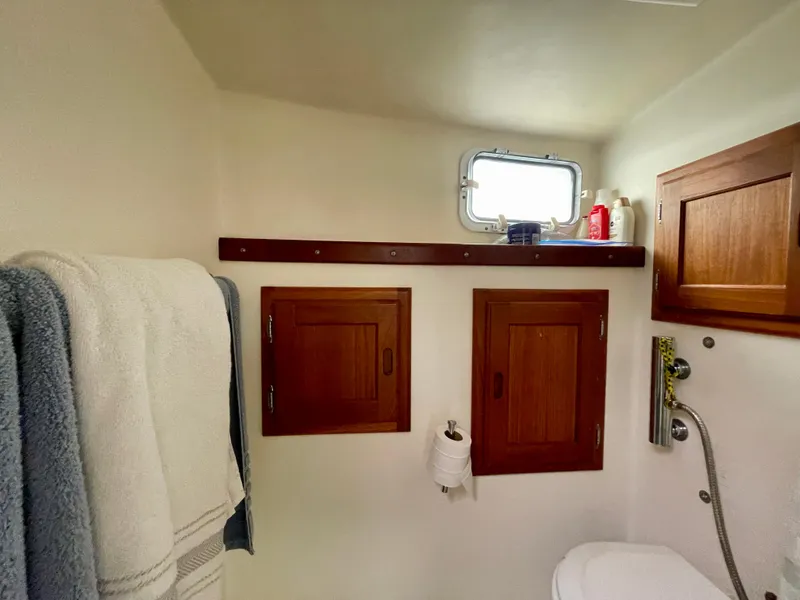 Slide: The Image of Small boat bathroom with wooden cabinets, towels, and a window. Beal 34, 2004 model. - 41
