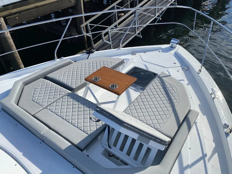 Slide: The Image of 2023 Cruisers Yachts 46 Cantius bow with cushioned seating and wooden table. - 16