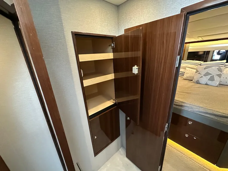 Slide: The Image of 2023 Cruisers Yachts 46 Cantius interior with open wooden cabinet and bedroom view. - 22