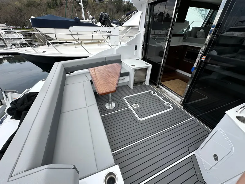Slide: The Image of 2023 Cruisers Yachts 46 Cantius deck with seating and table, docked at marina. - 40
