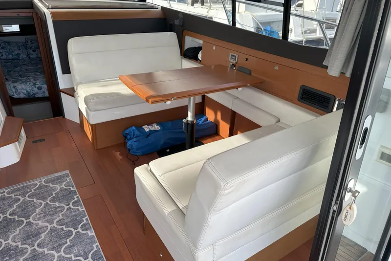 Slide: The Image of Interior of 2016 Jeanneau NC 11 boat with white seating and wooden table. - 8