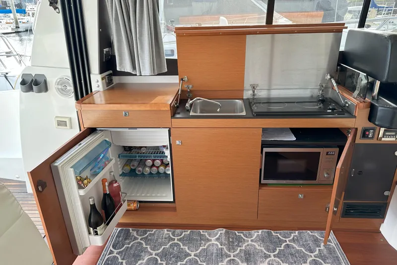 Slide: The Image of Compact kitchen area on a 2016 Jeanneau NC 11 boat with fridge, sink, and microwave. - 9