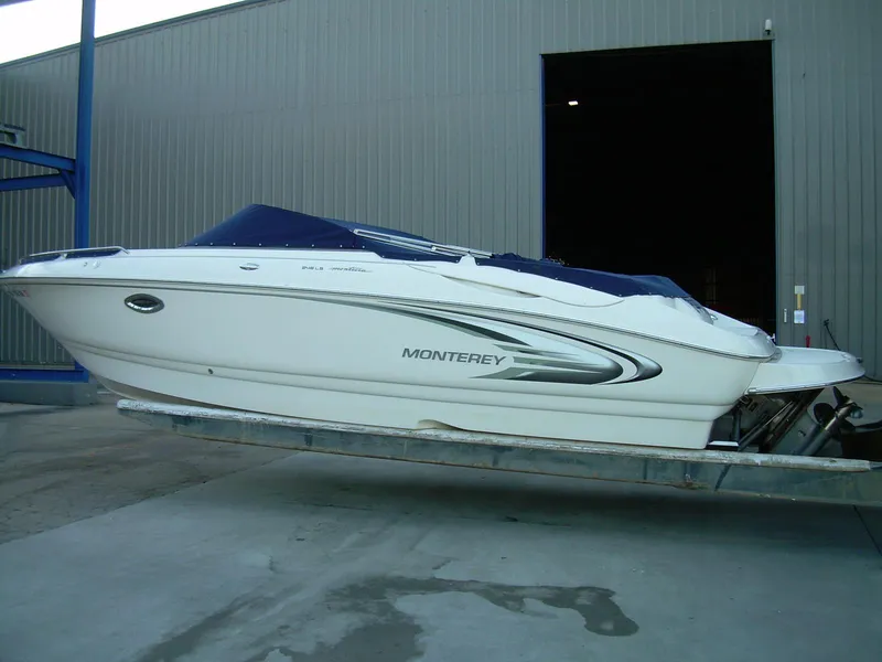 Slide: The Image of 2005 Monterey MONTURA 248 LS boat on trailer, parked outside a large building. - 2