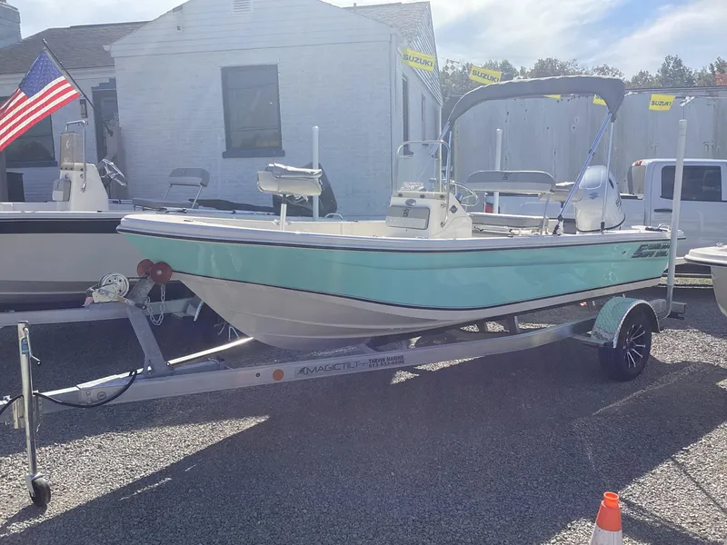 Slide: The Image of 2025 Carolina Skiff 178 JLS boat on trailer, displayed outdoors with American flag. - 13