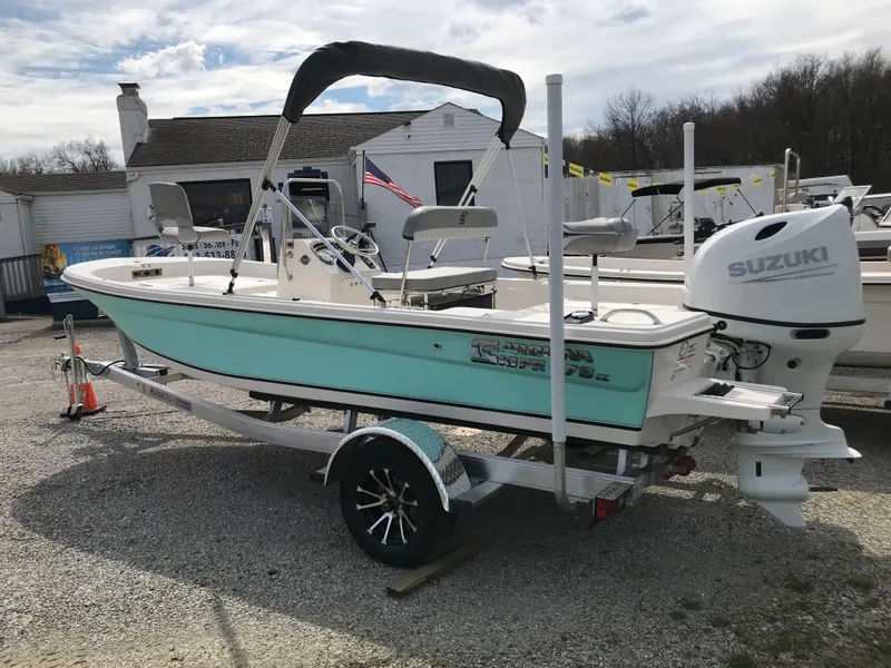 Slide: The Image of 2025 Carolina Skiff 178 JLS boat with Suzuki engine on trailer, parked outdoors. - 2