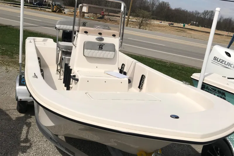 Slide: The Image of 2025 Carolina Skiff E18 JVX CC boat on trailer, parked near a road. - 2