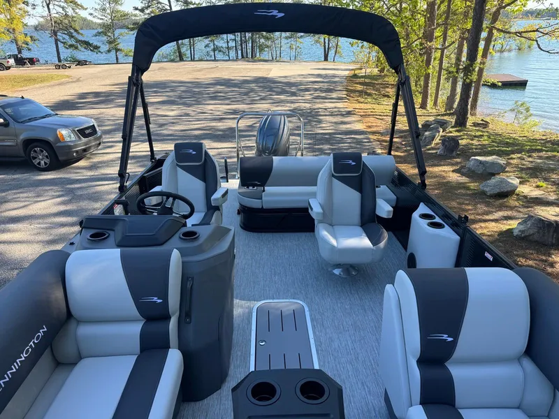 Slide: The Image of 2025 Bennington 22SSB pontoon boat with spacious seating, docked near a scenic lake. - 18
