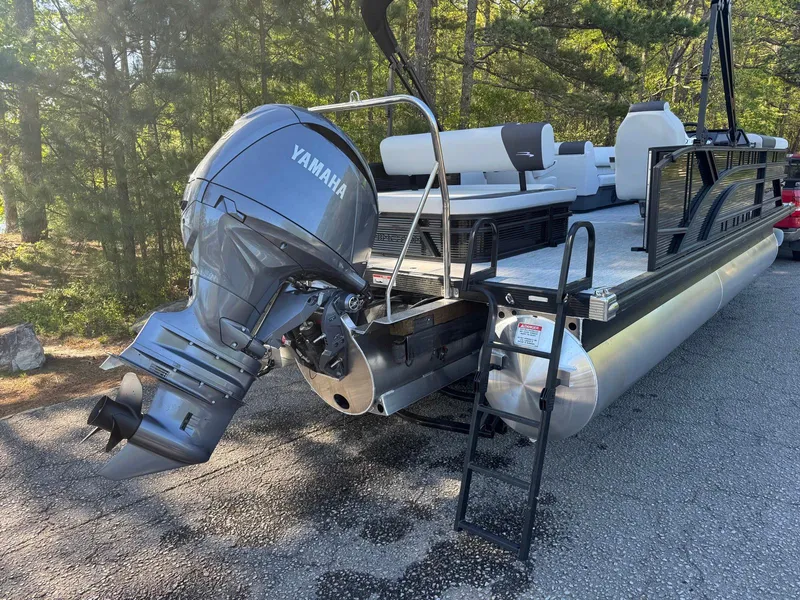 Slide: The Image of 2025 Bennington 22SSB pontoon boat with Yamaha outboard motor, parked on a forested road. - 19