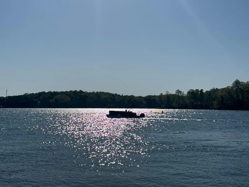 Slide: The Image of Pontoon boat on sparkling lake, Bennington 22SSB, 2025 model, under clear blue sky. - 2
