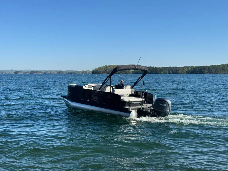 Slide: The Image of 2025 Bennington 22SSB pontoon boat cruising on a serene lake. - 4