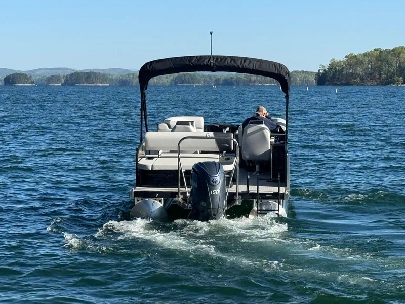 Slide: The Image of 2025 Bennington 22SSB pontoon boat cruising on a scenic lake. - 5