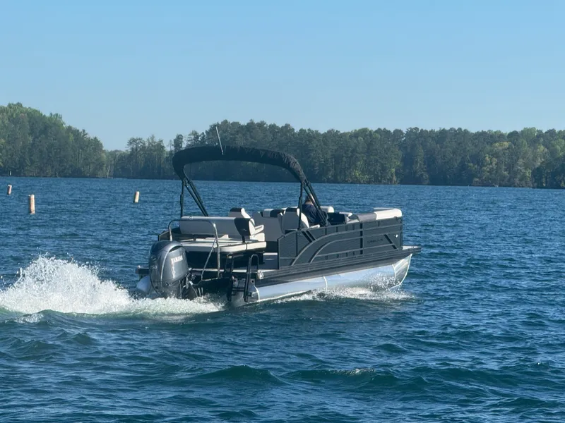 Slide: The Image of 2025 Bennington 22SSB pontoon boat cruising on a lake with forested shoreline. - 6