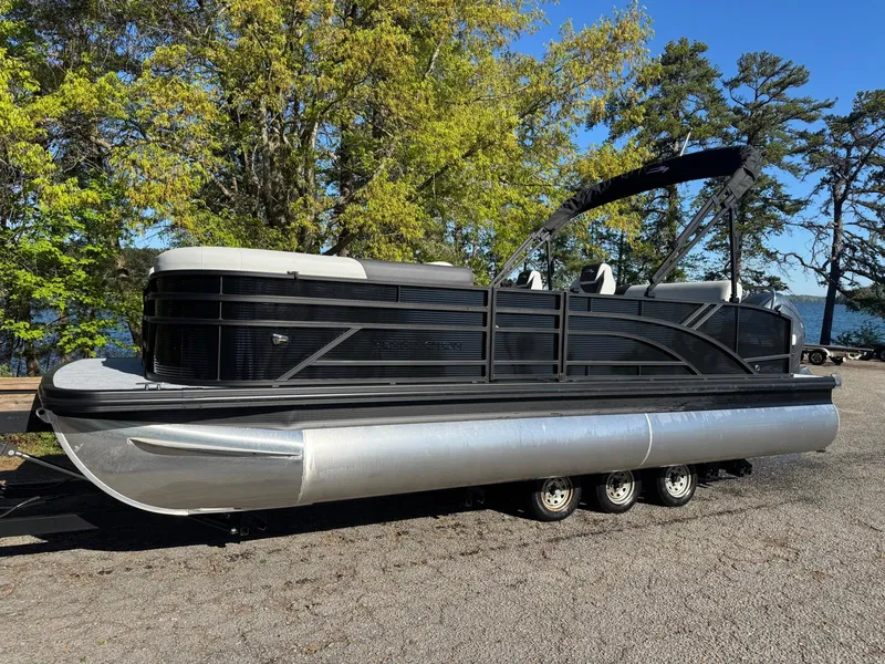 Slide: The Image of 2025 Bennington 22SSB pontoon boat on trailer, surrounded by trees and lake view. - 7