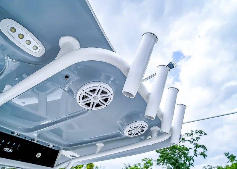 Slide: The Image of 2025 Sea Hunt Ultra 235 SE boat roof with speakers and rod holders against cloudy sky. - 22