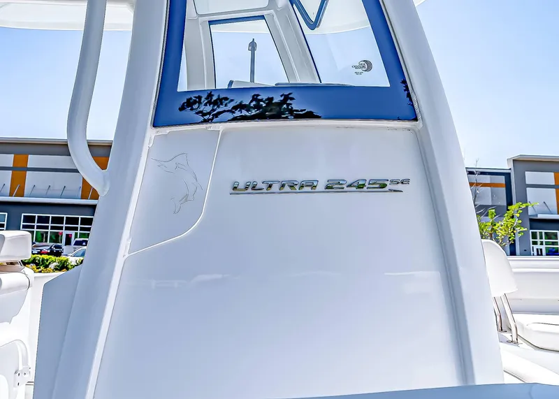 Slide: The Image of 2025 Sea Hunt Ultra 245 SE boat, sleek design with logo, against modern building backdrop. - 4