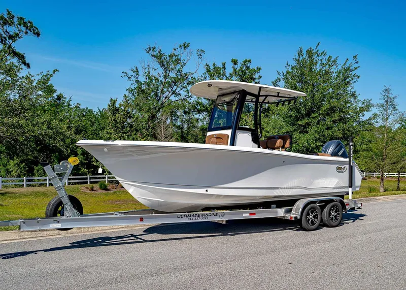 Slide: The Image of 2025 Sea Hunt Ultra 235 SE boat on trailer, parked on a sunny road. - 1