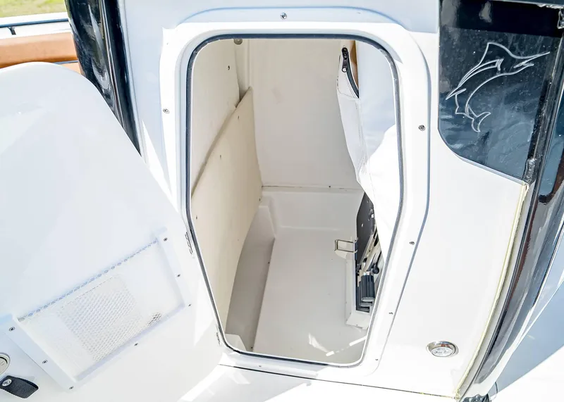 Slide: The Image of 2025 Sea Hunt Ultra 235 SE boat storage compartment with open door. - 16