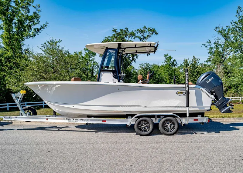 Slide: The Image of 2025 Sea Hunt Ultra 235 SE boat on trailer, parked on road with trees in background. - 2