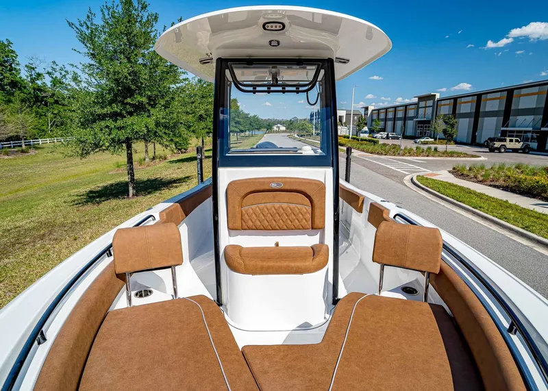 Slide: The Image of 2025 Sea Hunt Ultra 235 SE boat interior with brown seating, parked outdoors. - 21
