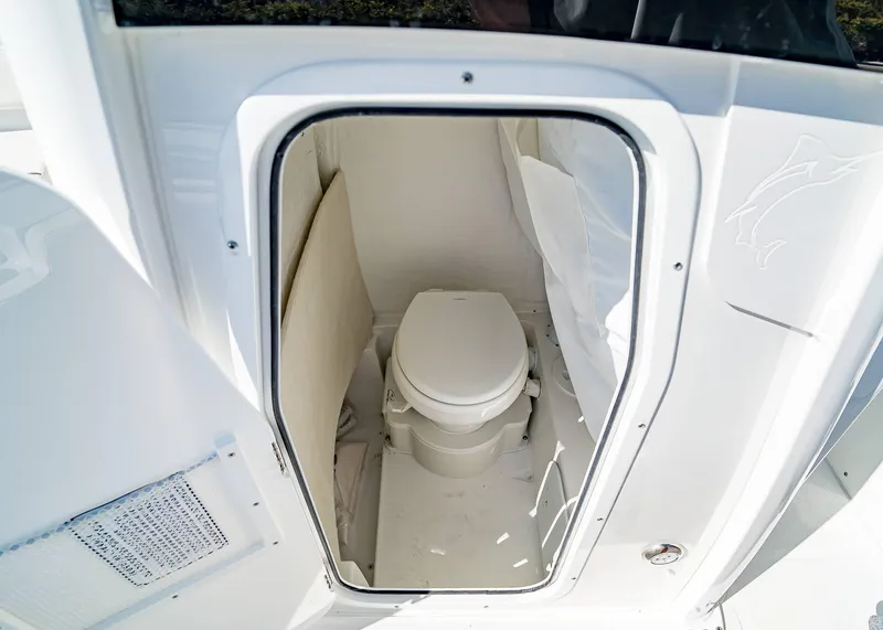 Slide: The Image of 2025 Sea Hunt Ultra 245 SE boat interior with compact marine toilet. - 17
