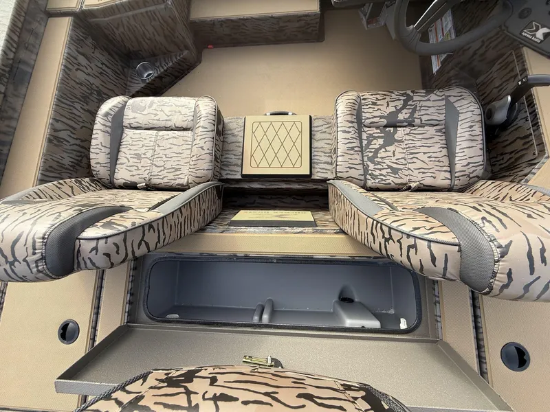 Slide: The Image of 2025 Xpress Hyper-Lift Bass Series boat interior with camo seats and storage compartment. - 7
