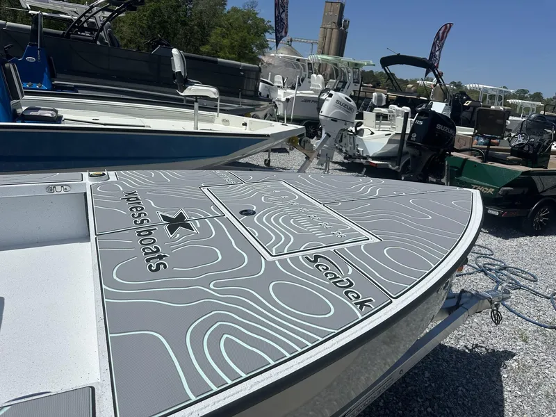 Slide: The Image of 2025 Xpress Skiff 185 boat with SeaDek flooring, displayed outdoors on gravel. - 3