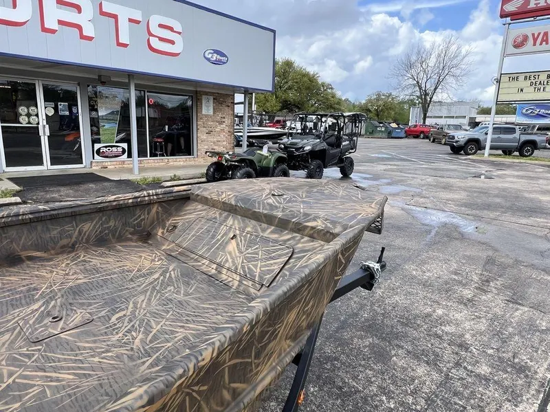 Slide: The Image of Camo-patterned G3 16 dk boat outside a sports dealership, 2025 model. - 10