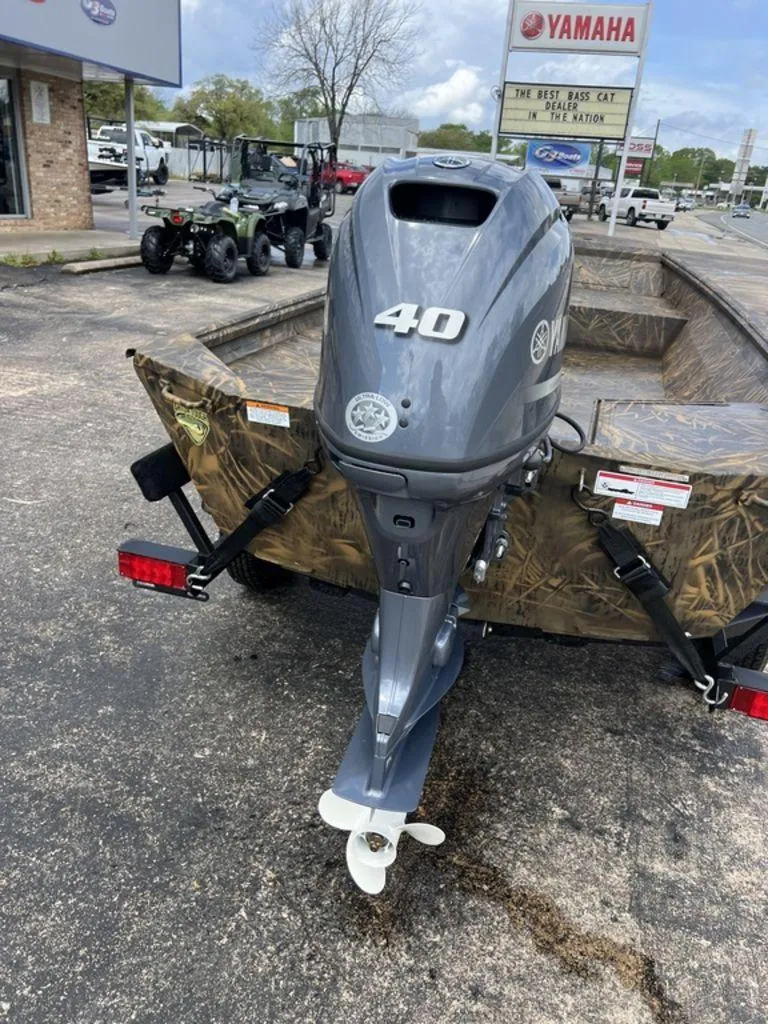 Slide: The Image of Outboard motor on a camo-patterned boat, parked near a Yamaha dealership. - 26