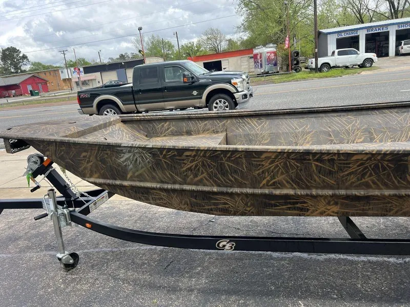 Slide: The Image of Camouflage-patterned G3 16 dk boat on trailer, parked near a road with vehicles in the background. - 41