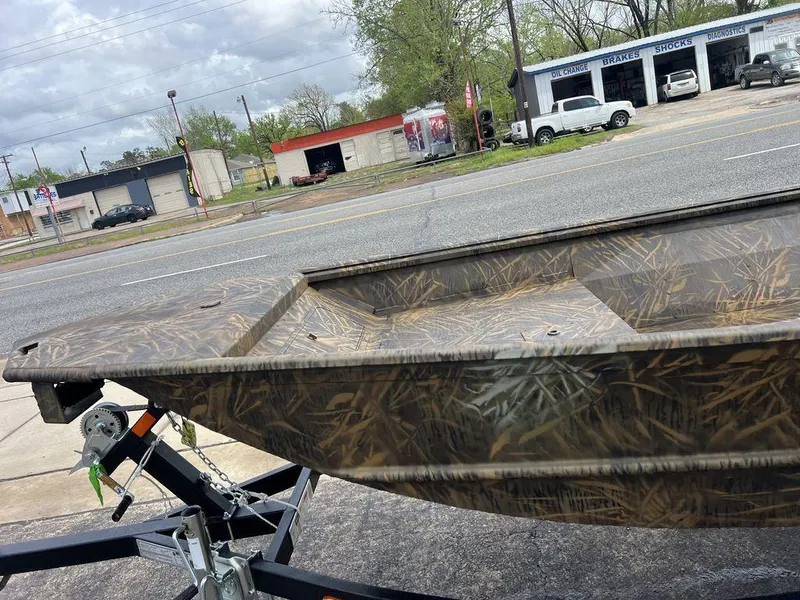 Slide: The Image of Camo-patterned G3 16 dk boat on trailer, parked near auto repair shops, 2025 model. - 45