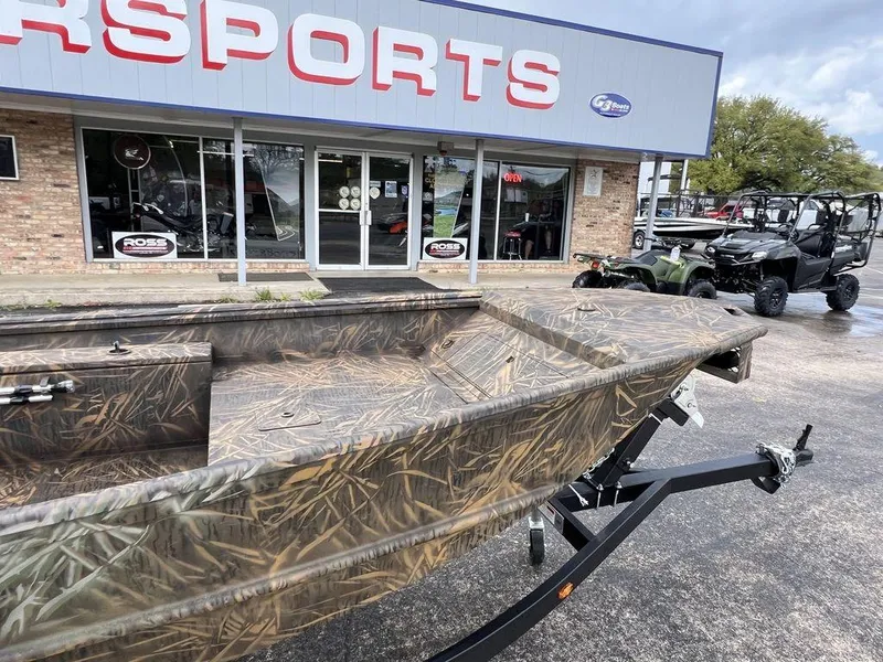 Slide: The Image of Camo-patterned G3 16 dk boat on trailer outside dealership, 2025 model. - 9