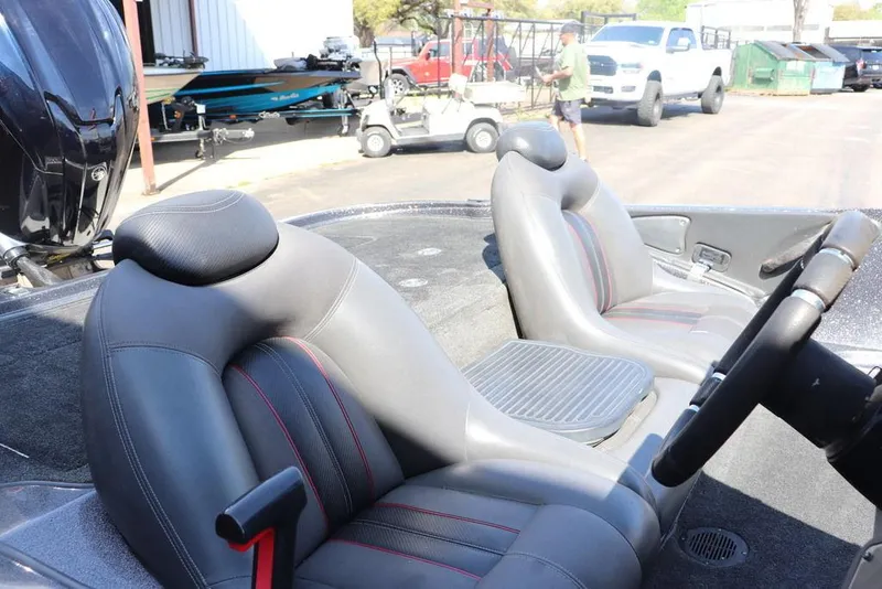 Slide: The Image of 2011 Ranger 518 boat interior with gray seats and steering wheel, parked outdoors. - 13
