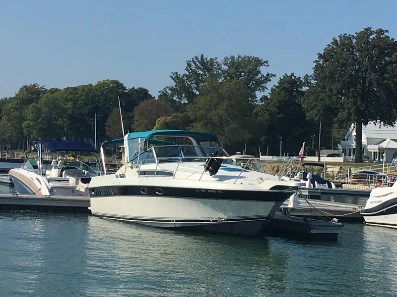 Slide: The Image of 1998 Wellcraft 3200 ST. Tropez docked at marina, surrounded by trees and boats. - 1