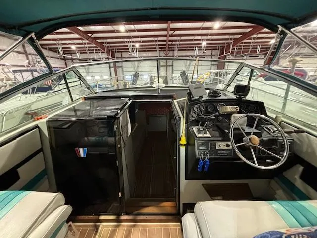 Slide: The Image of 1998 Wellcraft 3200 ST. Tropez boat interior with steering wheel and control panel in a storage facility. - 2