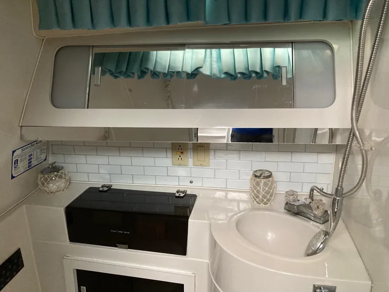 Slide: The Image of Bathroom interior of 1998 Wellcraft 3200 ST. Tropez with sink, mirror, and blue curtains. - 6
